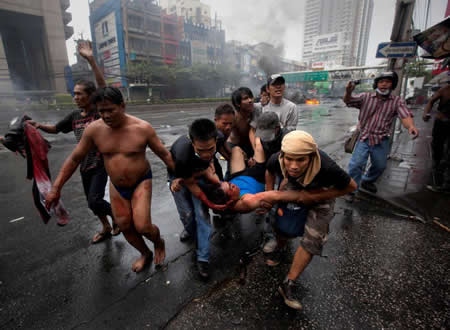 Membros do movimento anti-governamental 'Red Shirts' ('Camisas Vermelhas', em português) transportam um homem que foi baleado na cabeça durante confrontos com soldados do exército, em Banguecoque, na Tailândia. Créditos: Reuters / Adrees Latif Membros do movimento anti-governamental 'Red Shirts' ('Camisas Vermelhas', em português) transportam um homem que foi baleado na cabeça durante confrontos com soldados do exército, em Banguecoque, na Tailândia. Créditos: Reuters / Adrees Latif