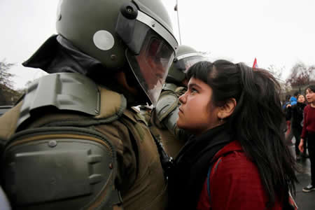 Uma manifestante olha para um policial de choque durante um protesto que marca o golpe militar de 1973 em Santiago, no Chile. Créditos: Reuters / Carlos Vera Uma manifestante olha para um policial de choque durante um protesto que marca o golpe militar de 1973 em Santiago, no Chile. Créditos: Reuters / Carlos Vera
