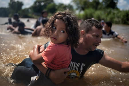 Luis Acosta segura Angel Jesus, de 5 anos, ambos das Honduras, numa caravana de migrantes da América Central a caminho dos Estados Unidos, ao atravessar o rio Suchiate para o México da Guatemala. Créditos: Reuters / Adrees Latif Luis Acosta segura Angel Jesus, de 5 anos, ambos das Honduras, numa caravana de migrantes da América Central a caminho dos Estados Unidos, ao atravessar o rio Suchiate para o México da Guatemala. Créditos: Reuters / Adrees Latif