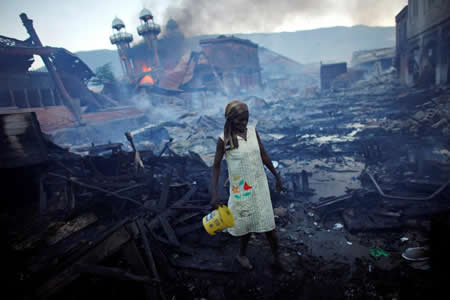 Uma mulher caminha num mercado devastado por um incêndio em Port-au-Prince, no Haiti. Uma mulher caminha num mercado devastado por um incêndio em Port-au-Prince, no Haiti.