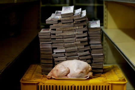 Uma galinha de 2,4 quilos é fotografada ao lado de 14.600.000 bolívares (moeda venezuelana), como representação do preço a que estaria a ser vendido nos supermercados de Caracas.  Créditos: Reuters / Carlos Garcia Rawlins  Uma galinha de 2,4 quilos é fotografada ao lado de 14.600.000 bolívares (moeda venezuelana), como representação do preço a que estaria a ser vendido nos supermercados de Caracas.  Créditos: Reuters / Carlos Garcia Rawlins