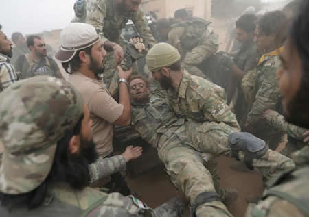 Rebeldes sírios apoiados pela Turquia ajudam um companheiro ferido, perto da cidade fronteiriça de Tal Abyad, na Síria. Rebeldes sírios apoiados pela Turquia ajudam um companheiro ferido, perto da cidade fronteiriça de Tal Abyad, na Síria.
