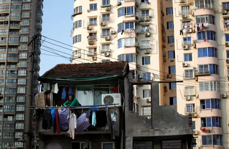 Uma mulher estende a roupa à janela da sua casa que será demolida para construção de novos apartamentos na baixa de Xangai, China. Uma mulher estende a roupa à janela da sua casa que será demolida para construção de novos apartamentos na baixa de Xangai, China.