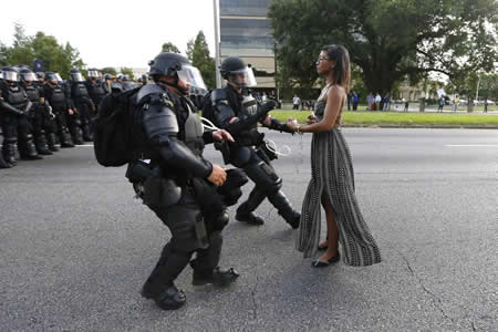 A ativista Leshia Evans mantém-se firme enquanto estende as mãos para ser detida pela polícia durante um protesto contra a brutalidade das forças de segurança, em Baton Rouge, no estado norte-americano do Louisiana. Evans, enfermeira da Pensilvânia com 28 anos e um filho, viajou até Baton Rouge para participar nos protestos contra a morte de Alton Sterling, de 37 anos e pai de cinco crianças, que foi baleado e morto por dois polícias. A ativista Leshia Evans mantém-se firme enquanto estende as mãos para ser detida pela polícia durante um protesto contra a brutalidade das forças de segurança, em Baton Rouge, no estado norte-americano do Louisiana. Evans, enfermeira da Pensilvânia com 28 anos e um filho, viajou até Baton Rouge para participar nos protestos contra a morte de Alton Sterling, de 37 anos e pai de cinco crianças, que foi baleado e morto por dois polícias.