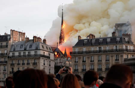Uma nuvem de fumo vai subindo enquanto o fogo consome o pináculo da Catedral de Notre Dame, em Paris (França). Uma nuvem de fumo vai subindo enquanto o fogo consome o pináculo da Catedral de Notre Dame, em Paris (França).