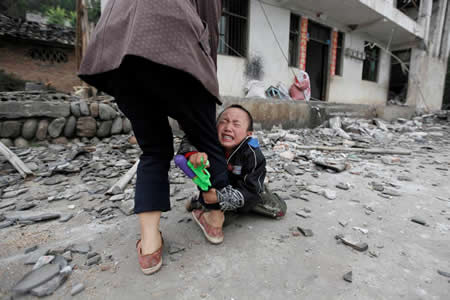 Um rapaz agarra a perna da sua mãe enquanto chora, em frente à casa onde viviam, destruída após um terramoto de magnitude 6,6 em Longmen, na província chinesa de Sichuan. Um rapaz agarra a perna da sua mãe enquanto chora, em frente à casa onde viviam, destruída após um terramoto de magnitude 6,6 em Longmen, na província chinesa de Sichuan.