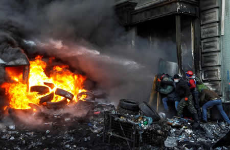 Apoiantes da integração da Ucrânia da União Europeia protegem-se de um jato de água durante as manifestações em Kiev.  Apoiantes da integração da Ucrânia da União Europeia protegem-se de um jato de água durante as manifestações em Kiev.