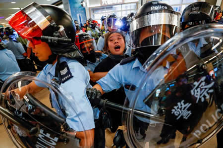 Polícia de Hong Kong detém mulher que protestava à frente de uma estação de comboio. Os manifestantes acusam a empresa ferroviária de estar do lado do Governo chinês Polícia de Hong Kong detém mulher que protestava à frente de uma estação de comboio. Os manifestantes acusam a empresa ferroviária de estar do lado do Governo chinês