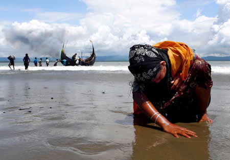 Uma refugiada Rohingya toca em terra, exausta, após ter atravessado de barco a fronteira entre o Myanmar e o Bangladesh.  Uma refugiada Rohingya toca em terra, exausta, após ter atravessado de barco a fronteira entre o Myanmar e o Bangladesh.