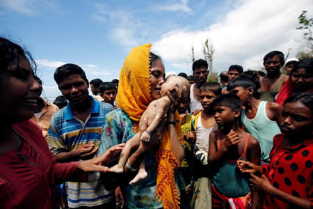 Uma refugiada Rohingya segura no seu filho de 40 dias, que morreu quando o bote onde seguiam afundou, na travessia entre o Myanmar e o Bangladesh.  Uma refugiada Rohingya segura no seu filho de 40 dias, que morreu quando o bote onde seguiam afundou, na travessia entre o Myanmar e o Bangladesh.