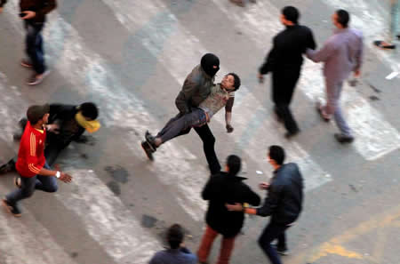 Manifestantes fogem do gás lacrimogénio atirado pela polícia durante os confrontos que seguiram a remoção de uma barreira de cimento na Praça Tahrir, no Cairo, Egito.  Manifestantes fogem do gás lacrimogénio atirado pela polícia durante os confrontos que seguiram a remoção de uma barreira de cimento na Praça Tahrir, no Cairo, Egito.