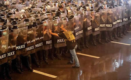 Anurak Jeantawanich, 52, empurra agentes da autoridade durante um protesto contra o governo em Banguecoque, na Tailândia. "Eu conseguia sentir o perigo a aproximar-se", disse Jeantawanich. "Olhei-os nos olhos e disse-lhes para não se aproximarem nem mais um pouco, que estavam muitos estudantes e raparigas jovens aqui". 