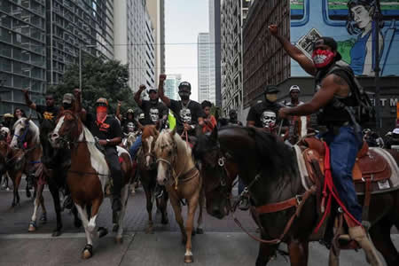 Manifestantes a cavalo, no centro de Houston, Texas, protestam contra a morte de George Floyd às mãos da polícia.

