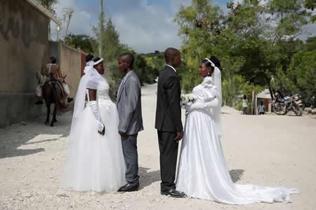 Casamento conjunto entre dois casais que não se conheciam para dividir os custos da cerimónia. Ambos os casais posam para uma foto fora da igreja onde se casaram em Baie de Henne, Nord Departamento de Ouest, Haiti.

