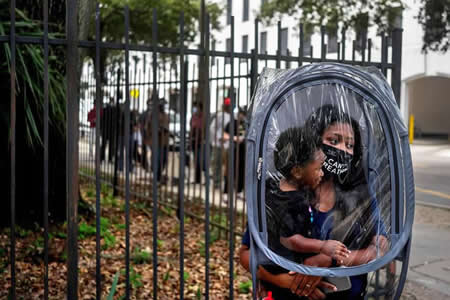Dana Clark e o filho Mason, de 18 meses, esperam na fila protegidos por uma capa enquanto esperam pelo início da votação para a eleição presidencial em Nova Orleans, Louisiana. Clark disse que colocou a capa protetora porque não sabia quantas pessoas estariam a usar máscaras na fila e porque o seu filho não tem uma máscara.

