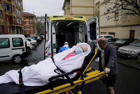 Maria Josefa Arias, de 76 anos, doente de covid-19, é colocada na ambulância pelo seu filho Ander Maria Dominguez Arias e a técnica de emergência Marisa Arguello de Paula, durante o surto de coronavírus, em Llodio, Espanha.