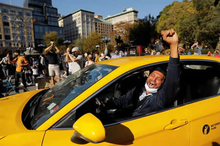 Um taxista celebra o anúncio dos media de que o candidato democrata, Joe Biden, venceu as eleições presidencias dos EUA, na Praça da União, em Manhattan, Nova Iorque.